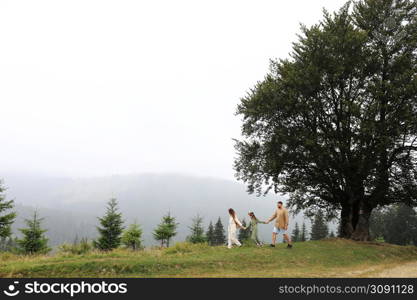 Young mom, dad with daughter travelling. parent playing and running with child outdoors, family trip in mountains. Active summer holidays. mothers, fathers and baby&rsquo;s day concept.. Young mom, dad with daughter travelling. parent playing and running with child outdoors, family trip in mountains. Active summer holidays. mothers, fathers and baby&rsquo;s day concept