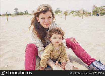 Young mom playing with her baby in the sand