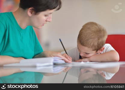 young mom woman doing home work with elementary school grade boy at home in kitchen