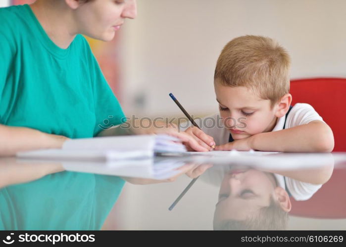 young mom woman doing home work with elementary school grade boy at home in kitchen