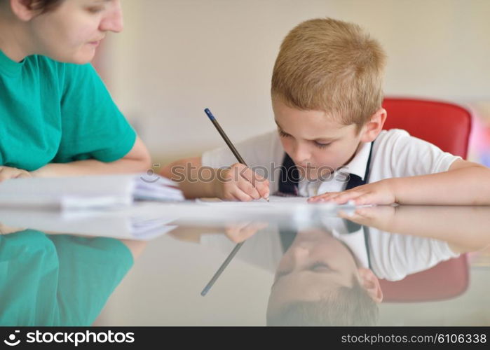 young mom woman doing home work with elementary school grade boy at home in kitchen