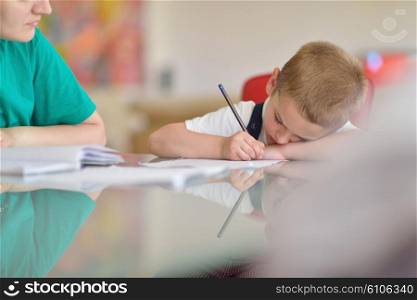 young mom woman doing home work with elementary school grade boy at home in kitchen
