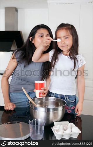 Young mother and cute little daughter cooking together