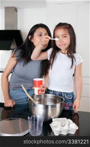 Young mother and cute little daughter cooking together