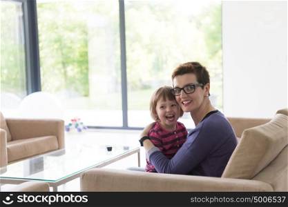 young mother and cute little girl enjoying their free time hugging on the sofa in their luxury home villa