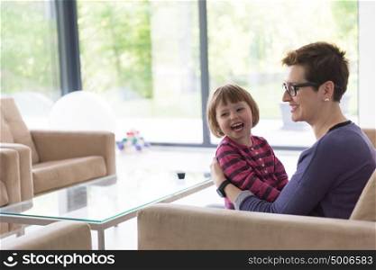 young mother and cute little girl enjoying their free time hugging on the sofa in their luxury home villa