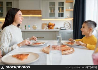 Young mother and cute little son eating ordered online pizza together sitting at dining room. Happy family at home. Young mother and cute little son eating pizza at home