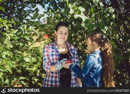 Young mother and daughter gardening at sunny summer day
