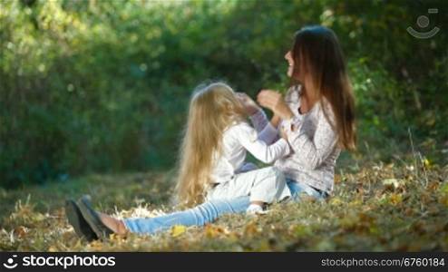 Young mother and daughter having a great day in the park, playing and laughing together