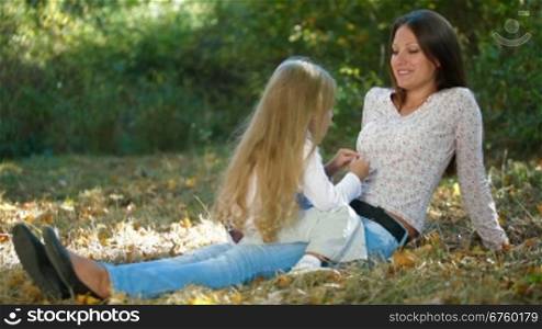 Young mother and daughter having a great day in the park, talking and laughing together