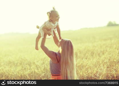 young mother and daughter kissing in the summer in wheat field