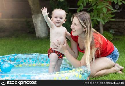 Young mother and her 9 months old baby in swimming pool at garden