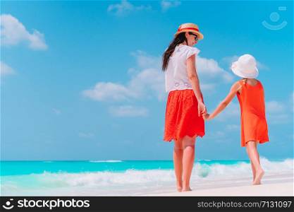 Young mother and her little daughter walk on the beach. Beautiful mother and daughter on Caribbean beach