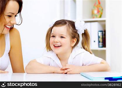 Young mother and her little girl studying together at home