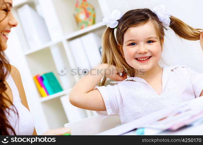 Young mother and her little girl studying together at home