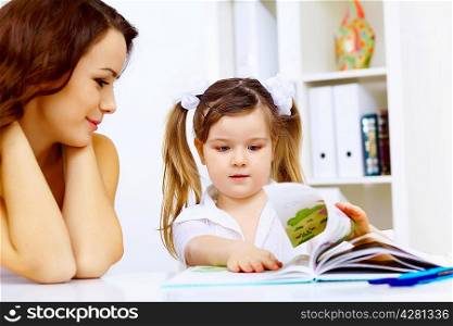 Young mother and her little girl studying together at home