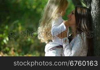 Young mother and little daughter enjoying autumn day in the park, playing