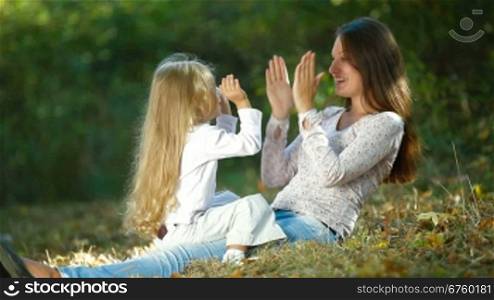 Young mother and little daughter having fun in the park