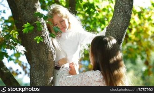 Young mother and little daughter having fun in the park, child kissing his mom