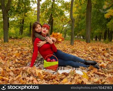 young mother and little daughters in bright sweaters on a picnic in nature relax. mom and daughter picnic