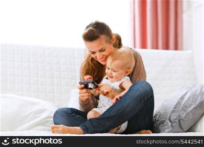 Young mother and smiling baby looking photos in camera at home&#xA;