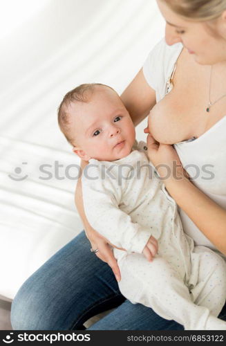 Young mother breastfeeding her 3 months old baby on bed