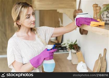 young mother cleaning shelves house