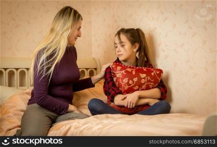 Young mother consoling teenage daughter on bed