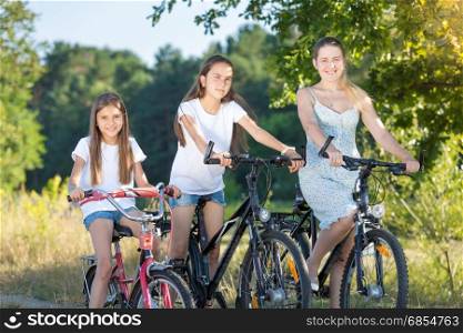 Young mother cycling with two daughters at meadow