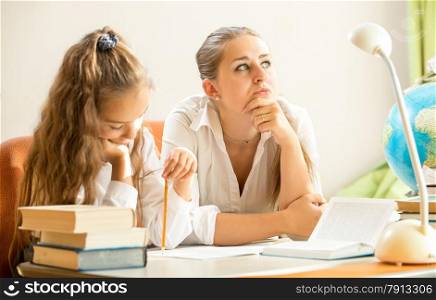 Young mother dreaming while daughter doing homework