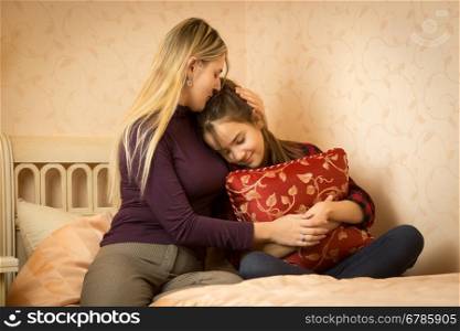 Young mother embracing and solacing teenage daughter at bedroom