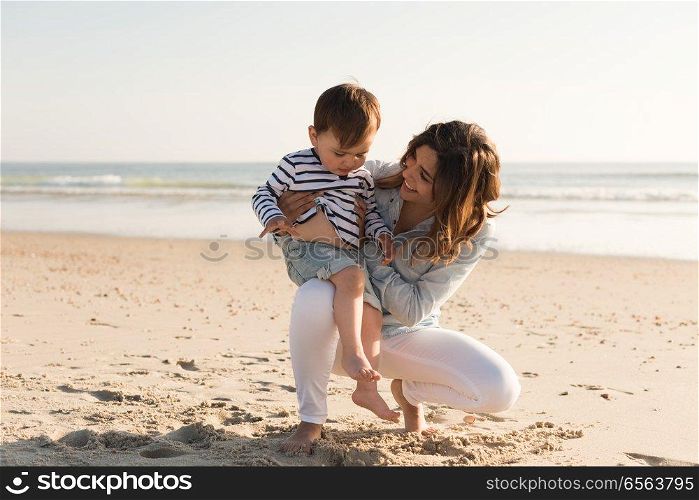 Young mother exploring the beach with toddler