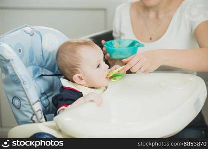 Young mother feeding her baby boy from spoon