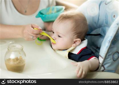 Young mother feeding her baby in highchair