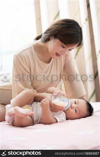 Young mother feeding her baby with milk