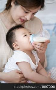 Young mother feeding her baby with milk