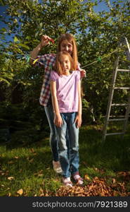 Young mother hanging daughter on string with clothespin