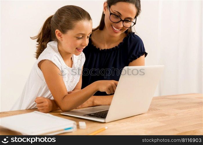 Young mother helping her daughter with homework at home