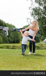 Young mother helping her little boy walk