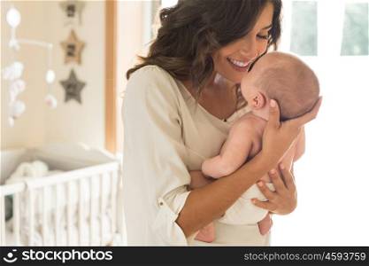 Young mother holding her baby in the bedroom