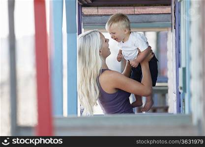 Young mother holding son (1-2) on outdoor porch