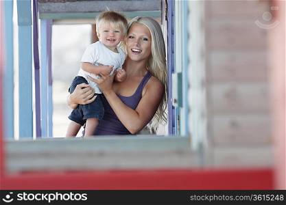 Young mother holding son (1-2) on outdoor porch, portrait