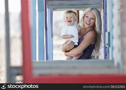 Young mother holding son (1-2) on outdoor porch, portrait