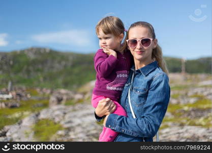 Young mother in sunglasses with her daughter at the hands of nature.