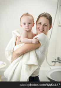 Young mother kissing her baby at bathroom after having bath