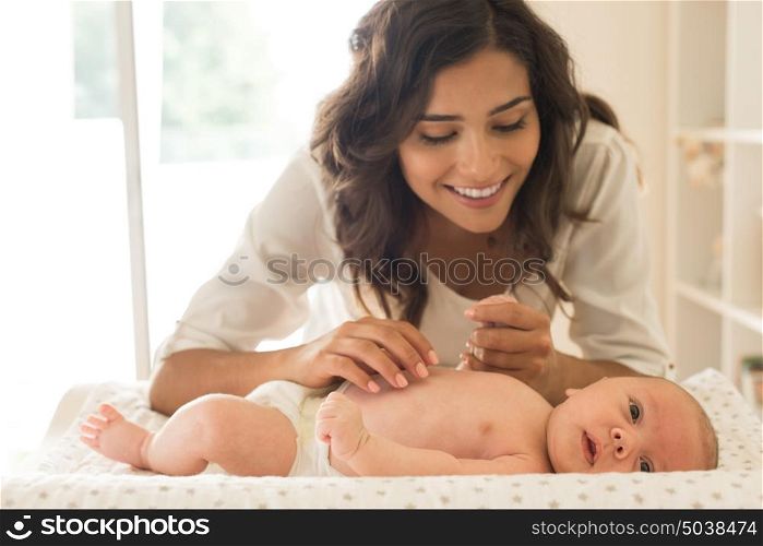 Young Mother moisturizing baby's skin after bath