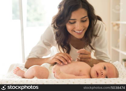 Young Mother moisturizing baby's skin after bath