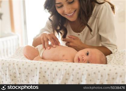 Young Mother moisturizing baby's skin after bath