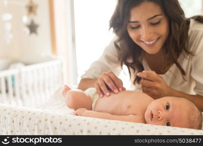 Young Mother moisturizing baby's skin after bath