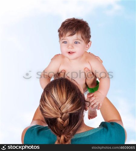 Young mother play with baby, lifting up her precious adorable son in the sky, having fun together outdoors, happy family life